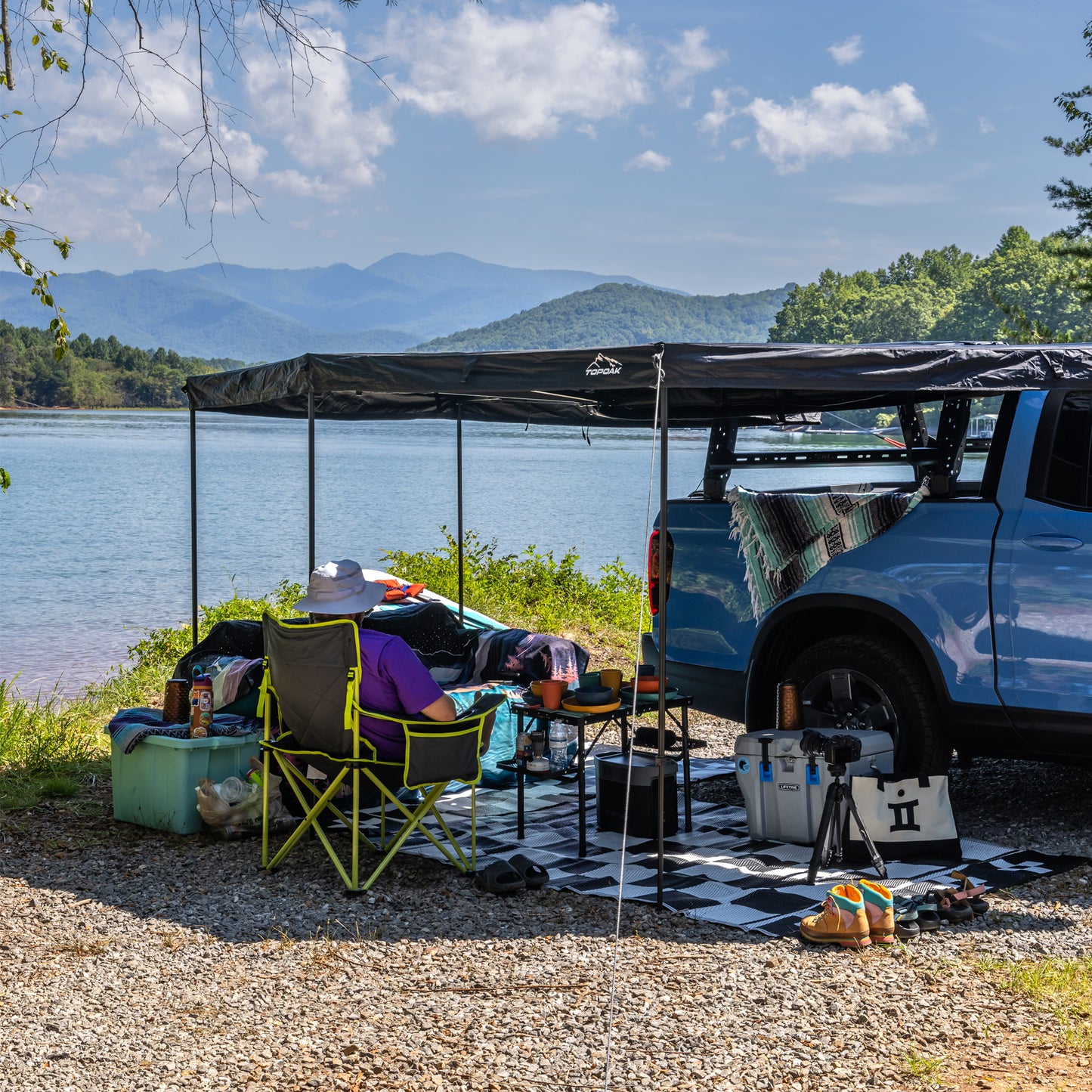 SUV car awning by lake with camper relaxing under shade