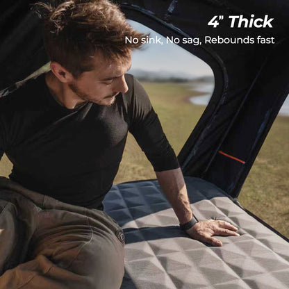 Inflatable mattress inside a rooftop tent demonstrating thickness and support under body weight.