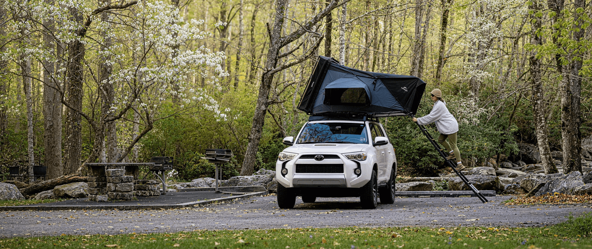 Overland SUV with rooftop tent camping in spring forest